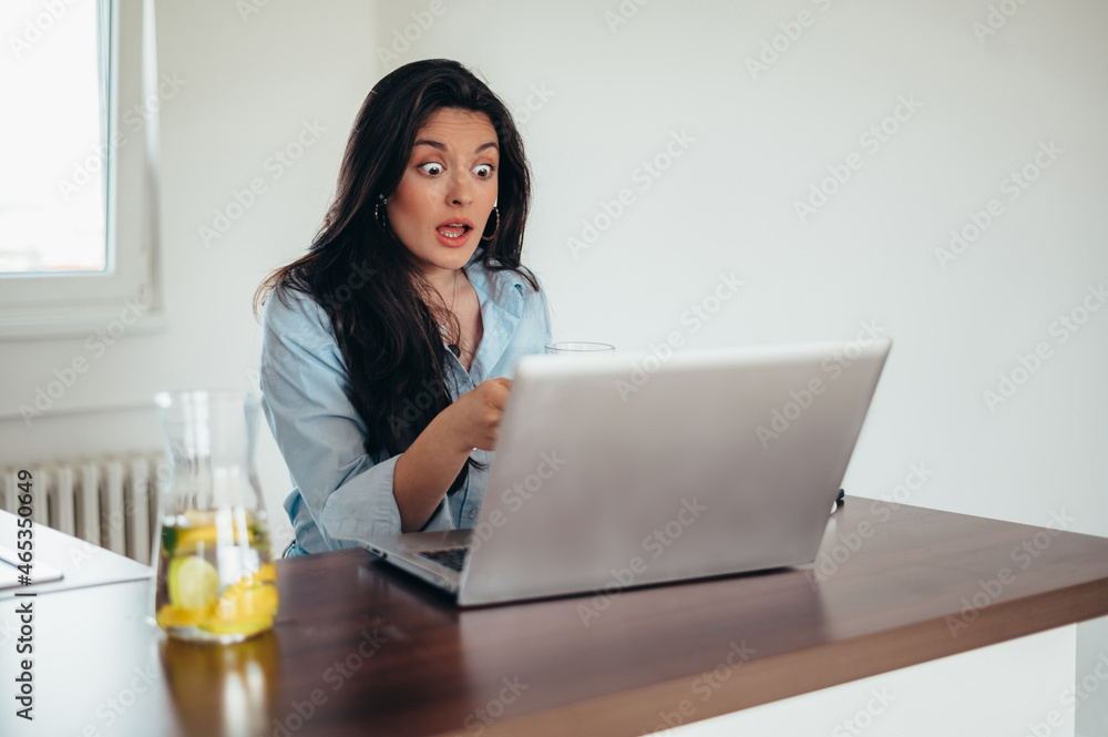 Businesswoman using a laptop while working in the kitchen at home Businesswoman using a laptop while working in the kitchen at home