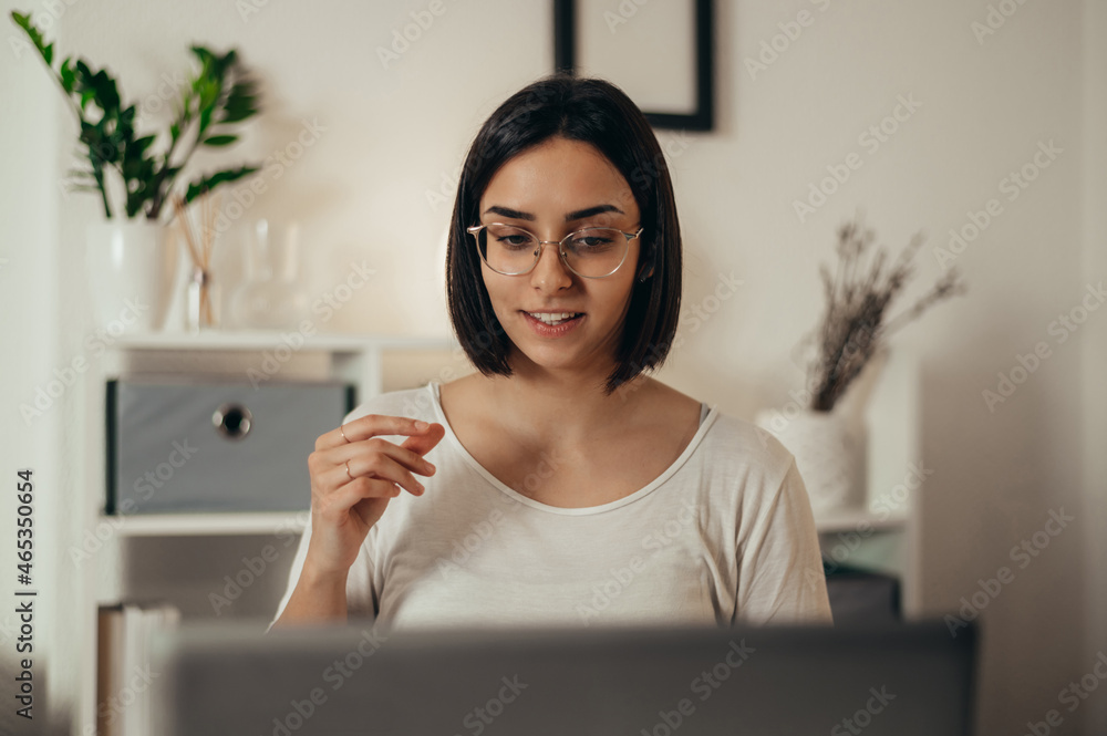Woman using a laptop for an online meeting while working from home Woman using a laptop for an online meeting while working from home