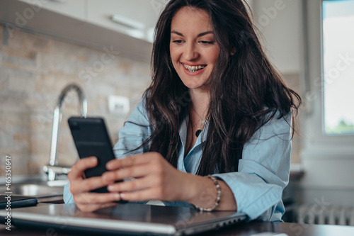 Woman taking selfie with a smartphone while working from home