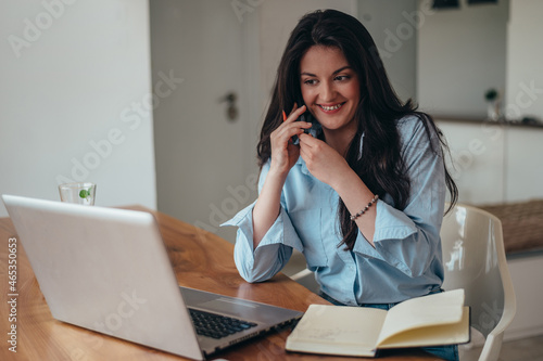 Young beautiful businesswoman using a laptop and a smartphone while in the office