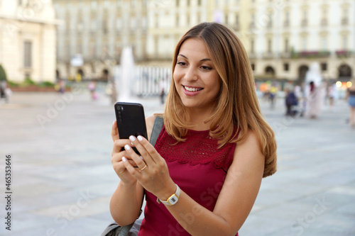 Vivacious young latin woman laughing using the smartphone for video calling outdoors