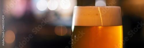 Платно full glass of beer on blurred lights background panorama