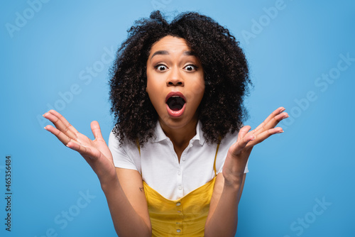 amazed african american woman with open mouth showing wow gesture isolated on blue photo