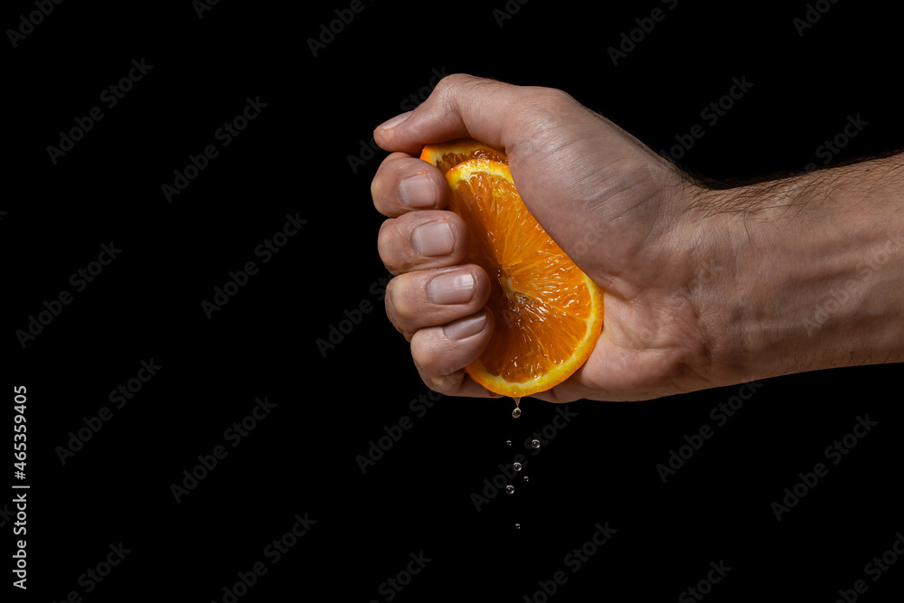 Hand squeezes juice from an orange on a black background. Fresh and juicy orange Hand squeezes juice from an orange on a black background. Fresh and juicy orange