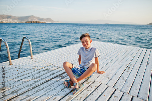Boy sit at Turkey resort on pier against Mediterranean sea.