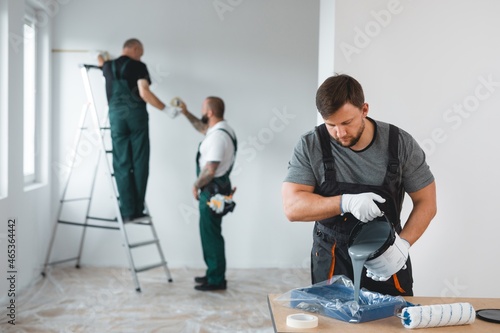 Billede på lærred Professional renovation crew painting walls of new build apartment