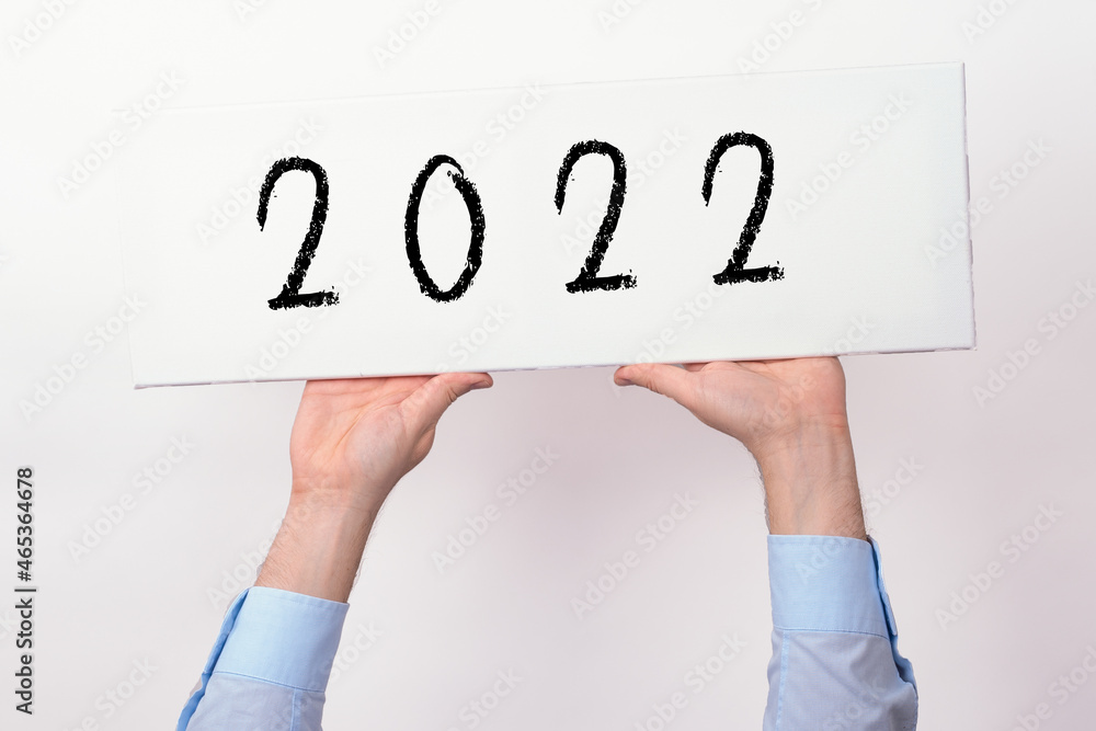 Zwei Hände halten ein Schild mit der Jahreszahl 2022 hoch Zwei Hände halten ein Schild mit der Jahreszahl 2022 hoch