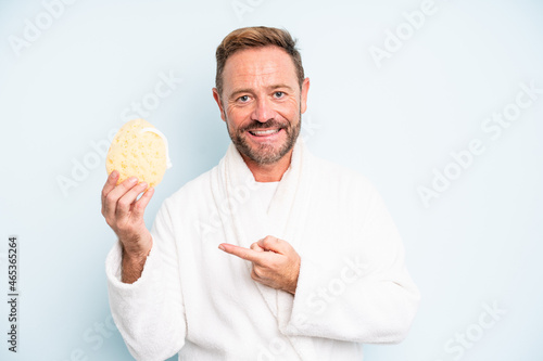 middle age man smiling cheerfully, feeling happy and pointing to the side. shower concept