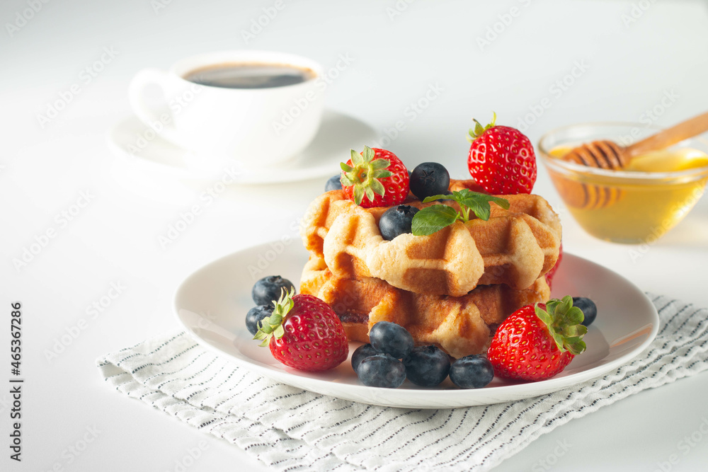 Fresh homemade food of berry Belgian waffles with honey, chocolate, strawberry, blueberry, maple syrup and cream. Healthy dessert breakfast concept with juice Fresh homemade food of berry Belgian waffles with honey, chocolate, strawberry, blueberry, maple syrup and cream. Healthy dessert breakfast concept with juice