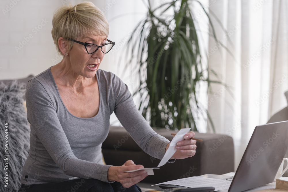Worried senior woman working on a computer at home, calculating monthly expenses, mortgage payments, having financial problems Worried senior woman working on a computer at home, calculating monthly expenses, mortgage payments, having financial problems