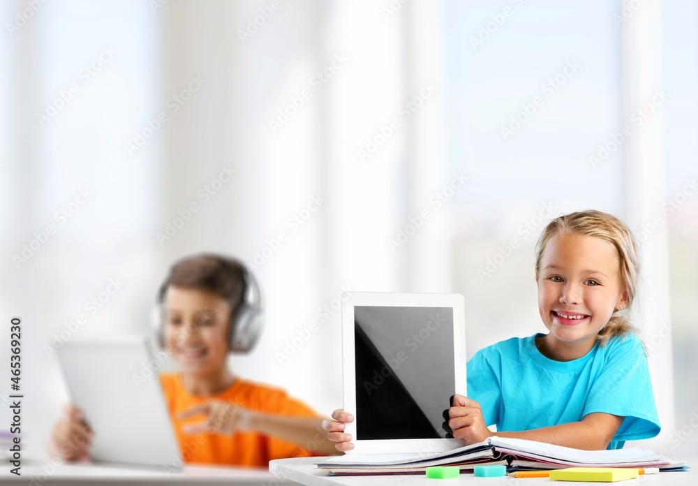 Happy school dhild holding device using digital tablet computer at class in classroom. Happy school dhild holding device using digital tablet computer at class in classroom.