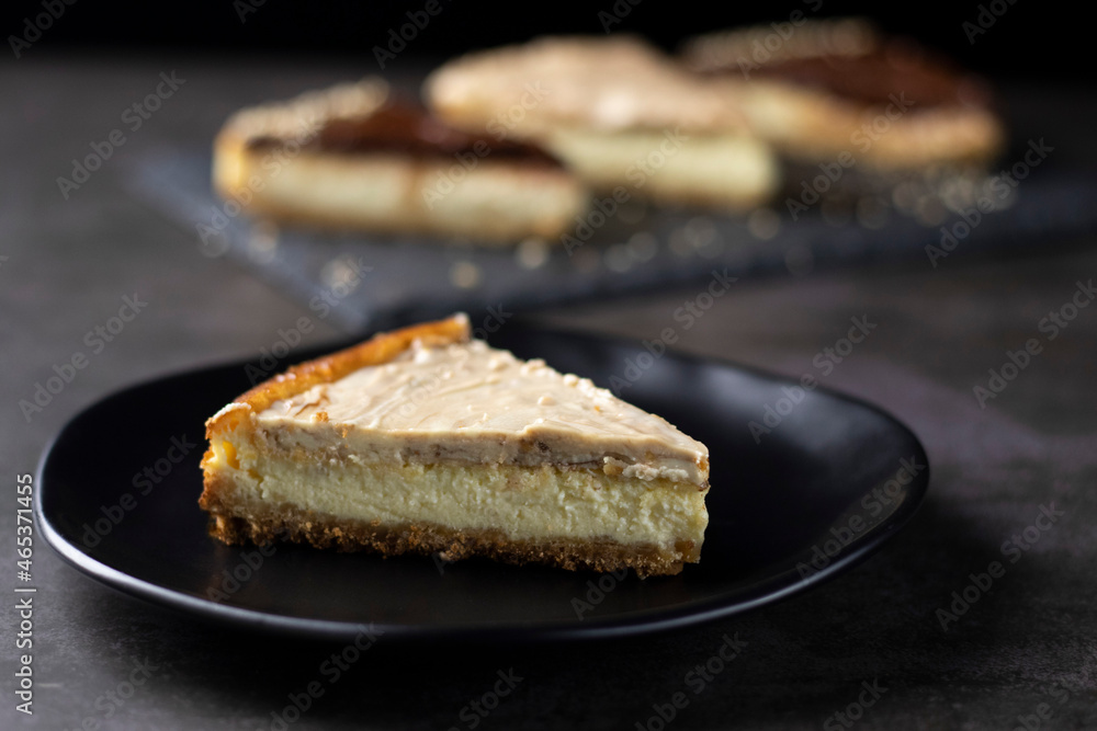Cheesecake of white chocolate cream and peanut on black plate Cheesecake of white chocolate cream and peanut on black plate