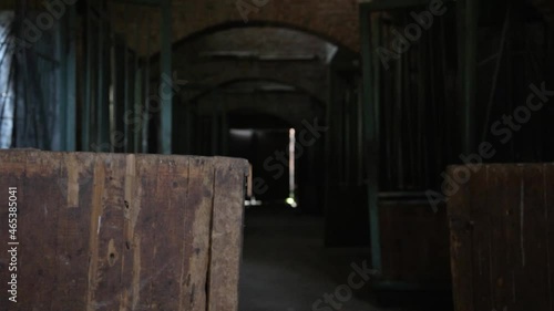 One sash of a wooden gate in a dark deserted barn opening wide