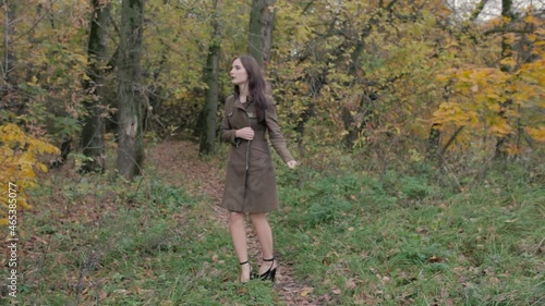 Lonely girl in a coat on the edge of the forest is afraid of something and hides behind a tree