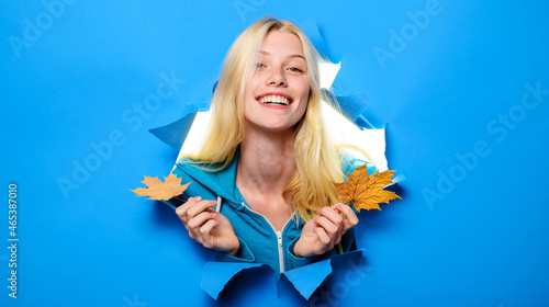 Autumnal mood. Smiling woman with maple leaves looking through paper hole. Discount. Season sales. Advertising.