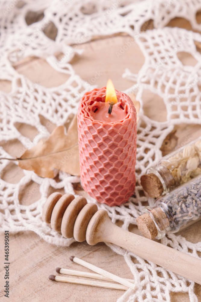 Handmade scented candle for interior. Lighted beeswax candle on wooden and lace background