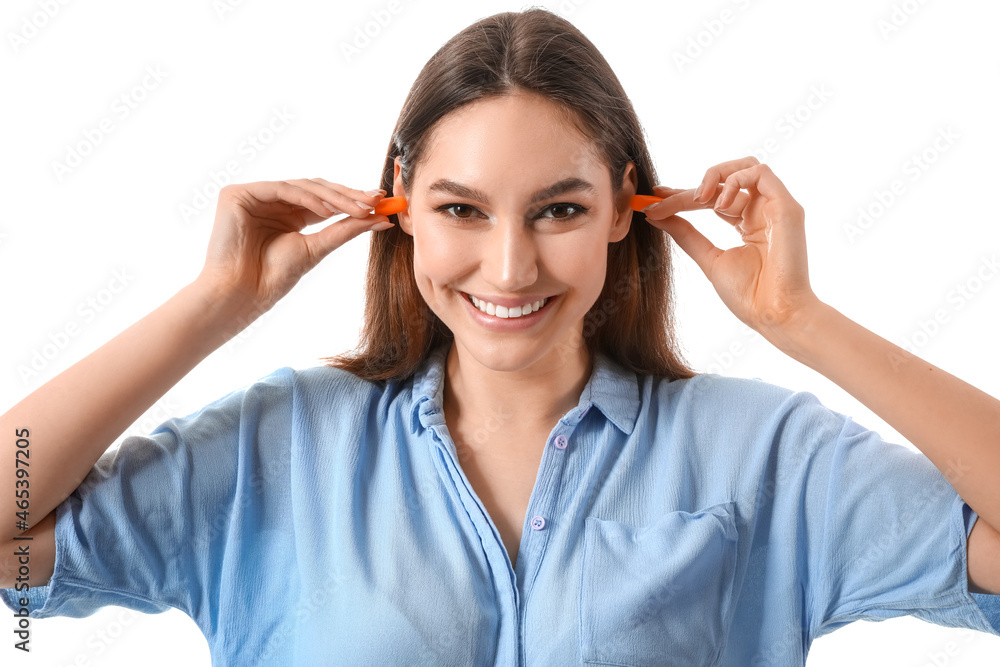 Young woman inserting earplugs on white background Young woman inserting earplugs on white background