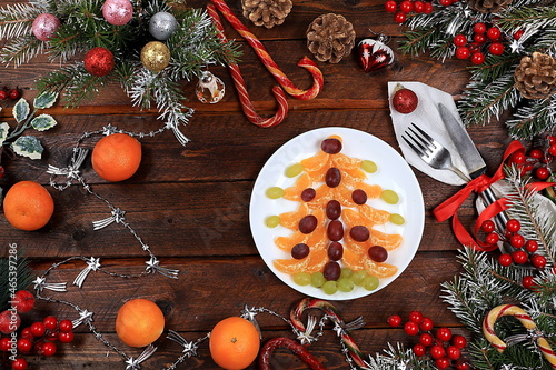 Christmas new year dishes, for traditional festive tangerine and grape salad with sweets, fir branches and cones and decorations, food design idea, place for recipe, flat lay, photo