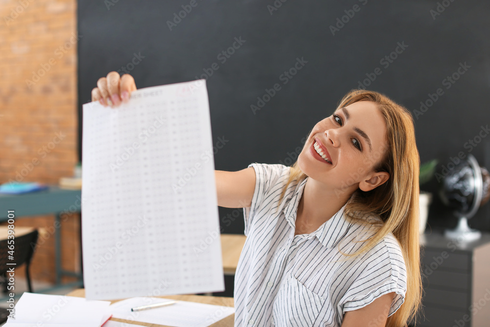 Fototapeta premium Happy student with answer sheet for school test in classroom