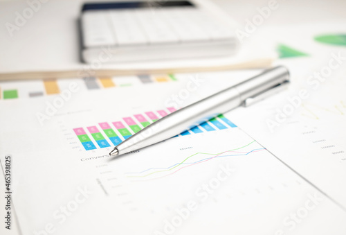 closeup blue graph and chart reports and pen on office table, financial and business concept