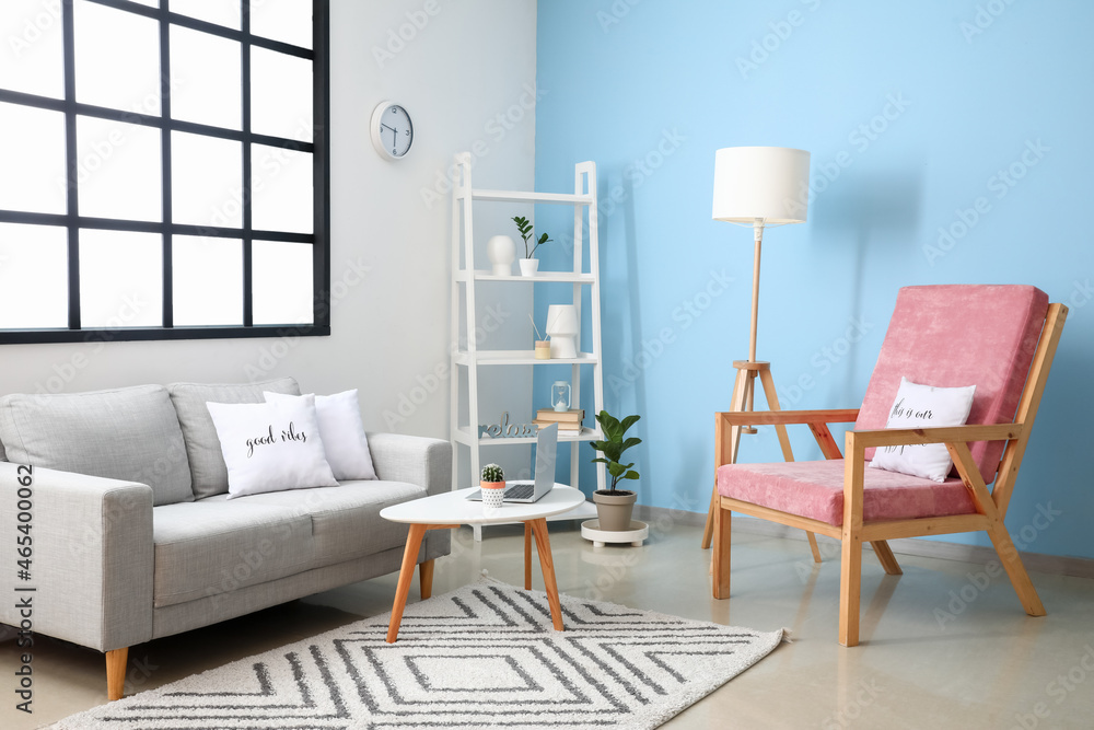 Interior of modern room with stylish armchair and sofa near window and color wall Interior of modern room with stylish armchair and sofa near window and color wall