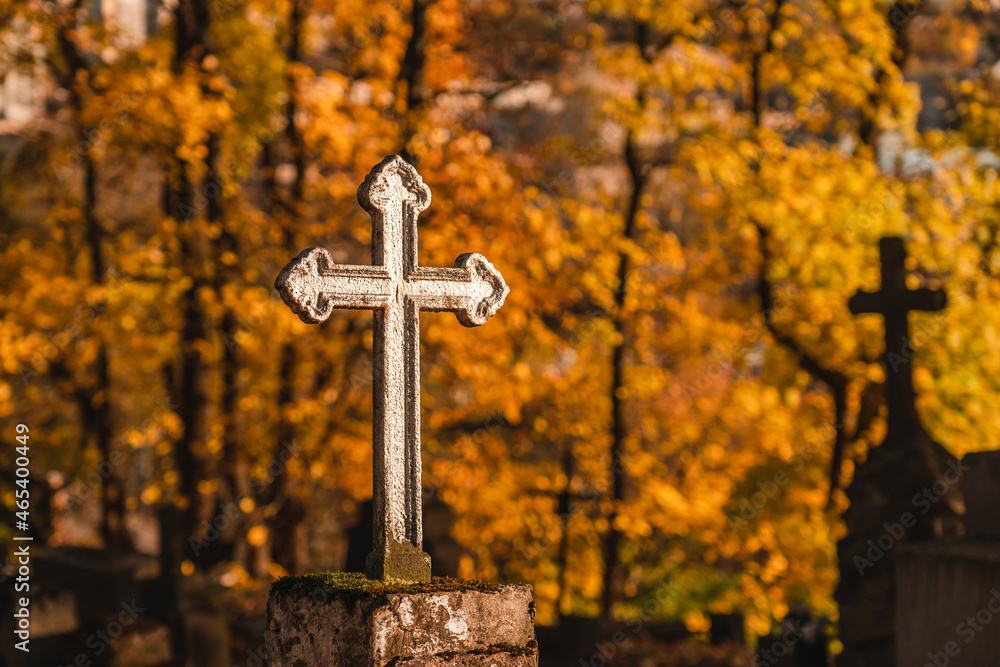 a close up of a metal cross at a cemetery in autumn