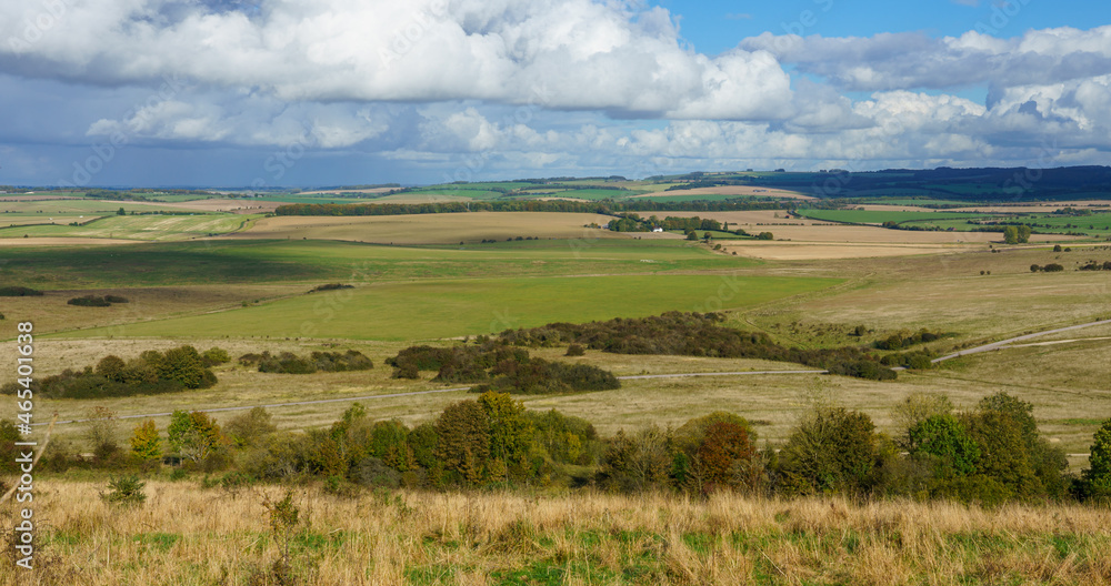 a view over woodland and meadows East of Everleigh from Sidbury Hill, WIltshire (Historical landmark) under a blue and white cloud sky a view over woodland and meadows East of Everleigh from Sidbury Hill, WIltshire (Historical landmark) under a blue and white cloud sky