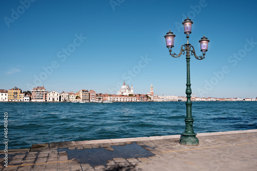 Fototapeta Naklejka Na Ścianę i Meble -  Italy, Venice, old street lamp on Guidecca promenade. Venice skyline with Punta della Dogana, church Santa Maria della Salute and St Mark's Campanile tower across the water on the background.