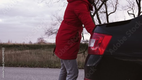 A woman takes a fire extinguisher out of the trunk of a car.