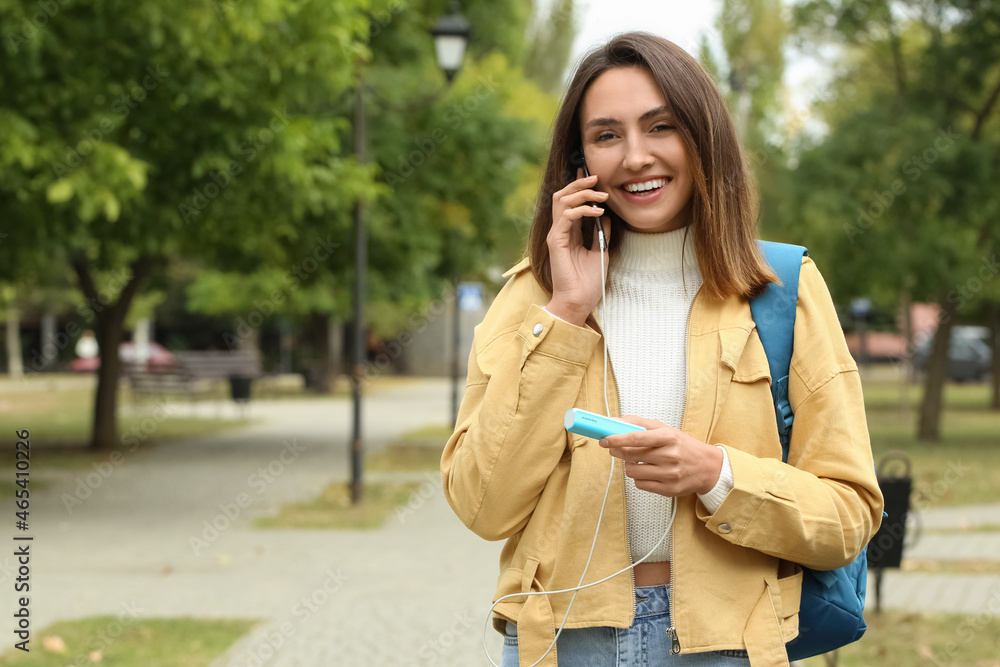 Young woman with phone and power bank outdoors Young woman with phone and power bank outdoors