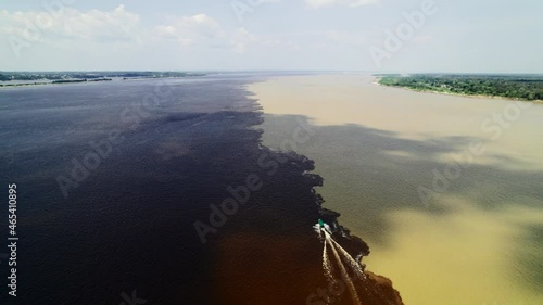 The boat sails on the border of two rivers of the Amazon. The confluence of two dark and light waters of the Encontro das Aguas and Rio Negro straits.