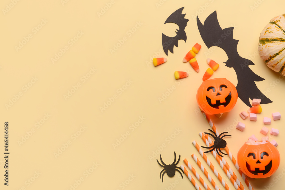 Pumpkins with candies and Halloween decor on beige background