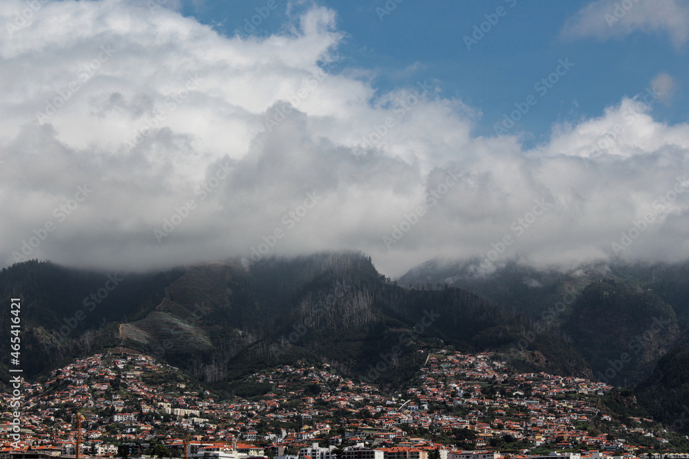 Houses on the hillside with the mountains and clouds over the mountains in Funchal, Portugal Houses on the hillside with the mountains and clouds over the mountains in Funchal, Portugal
