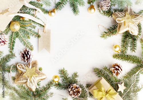 A Christmas flatlay  with Christmas tree branches, cones, a gift bag and decorations. On a white wooden background , copy space , mock up