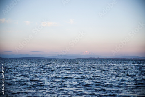 Shot of mount baker in a distant pink sky with the ocean in the foreground