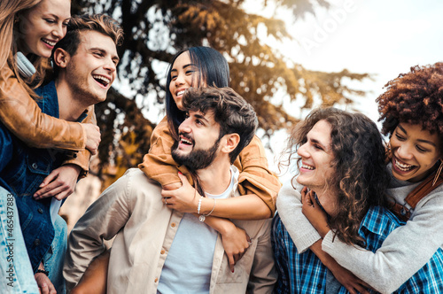 Millennials friends on vacation having piggyback race on city street - Young people group enjoying time together laughing outdoors - Summer vacations, friendship and happy lifestyle concept