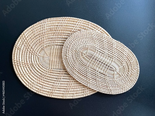Oval shaped woven rattan placemat on black background, handmade kitchenware, weave craft product