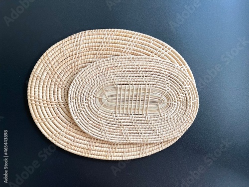 Oval shaped woven rattan placemat on black background, handmade kitchenware, weave craft product