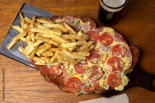 Neapolitan Milanese with mozzarella and sliced tomato garnished with French fries and beer on wooden board