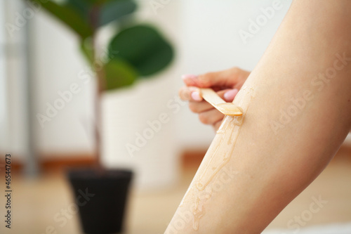 Woman during the procedure of waxing women's legs with wax strips on women's legs at home.
