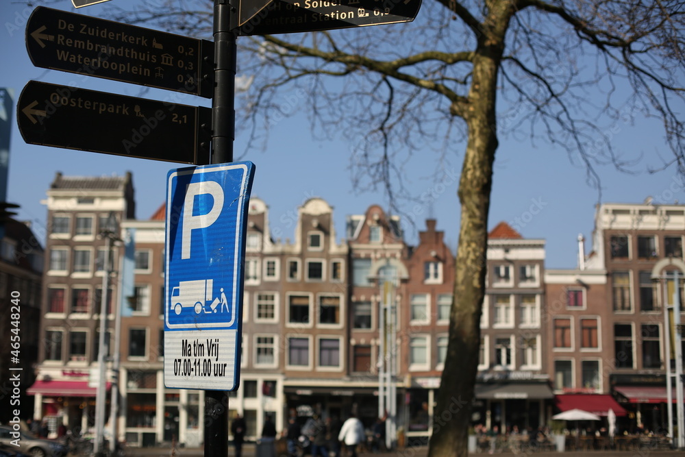 traditional brick houses and a blue parking sign on the street of amsterdam