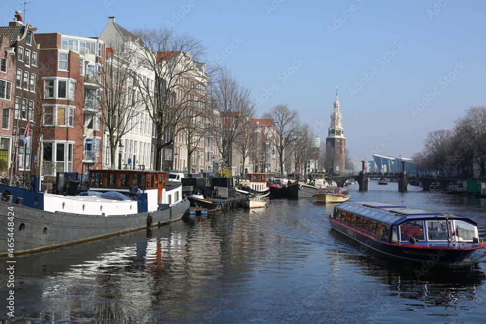 cityscape of traditional brick houses and boat houses floating in canal of winter amsterdam