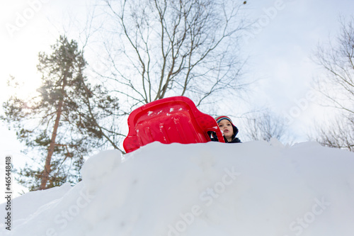 Low angle view of a boy sledding on a snow hill in winter