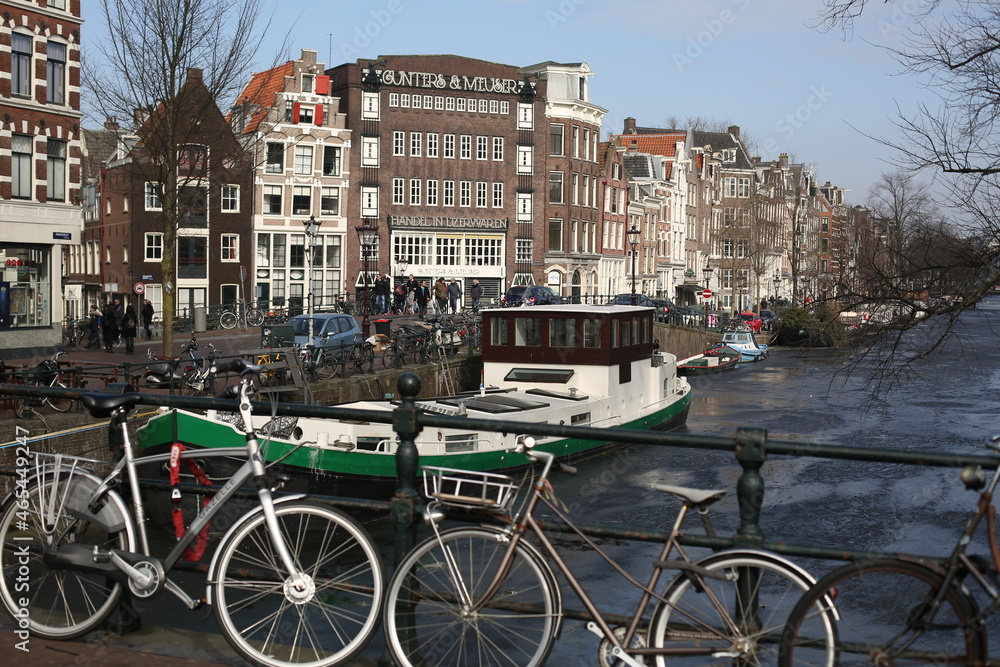 scenery of traditional brick houses, ship sailing in canal, and parking bicycles on the street in amsterdam