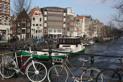 scenery of traditional brick houses, ship sailing in canal, and parking bicycles on the street in amsterdam