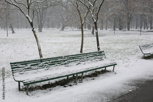 a long bench in snow-covered park in milano city