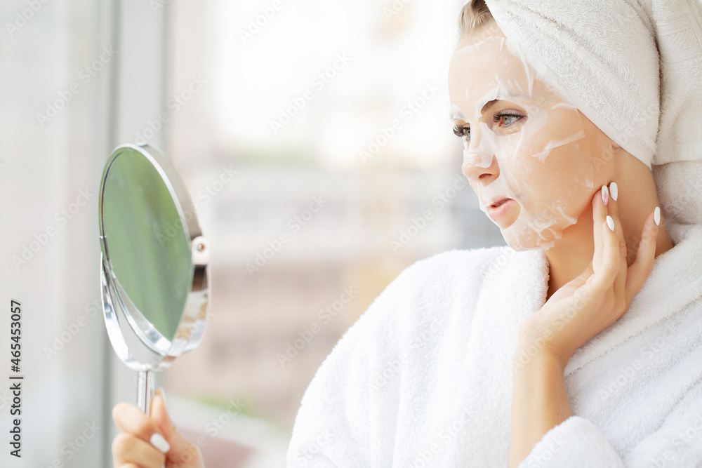 Beautiful young woman is applying a cosmetic tissue mask on a face Beautiful young woman is applying a cosmetic tissue mask on a face