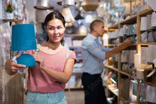 Woman is choosing new table lamp for her home in the store