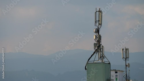 Mobile phone communication tower on building roof on mountain and sky background. Technology of telecommunication GSM tower. 5G or 4G concept