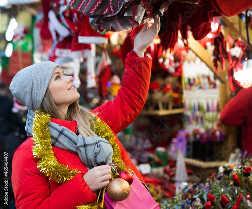 Young smiling woman choosing Xmas decoration on outdoor market